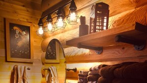 Ein rustikales Badezimmer einer Holzhütte mit einem Holzbac, einem Spiegel, einer Toilette und einem Regal mit Handtüchern.