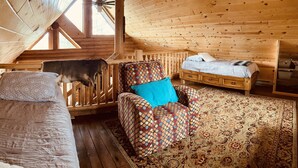 Eine Holzhütte mit Schlafkoje, einem gemusterten Sessel und einem kleinen Sofa.