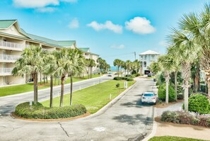 A hotel with a curved driveway, palm trees, and a view of the ocean.