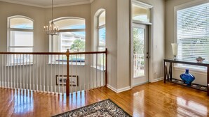 A spacious room with wooden flooring, a chandelier, and a view through large windows. - Bird of Paradise, see the # of 5-stars-Just steps from Beach (Miramar Beach)