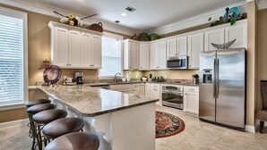 A kitchen with white cabinets, a stainless steel refrigerator, a microwave, and a granite countertop. - Bird of Paradise, see the # of 5-stars-Just steps from Beach (Miramar Beach)