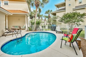 A swimming pool with lounge chairs and a covered grill area.