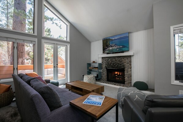 A modern living room with a stone fireplace, a large window, and a view of the outdoors.