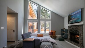 A bedroom with a large window, a fireplace, and a bed with a view of the outdoors. - Cozy Updated McCloud Condo - Walk to Lakeshore Drive, Shops & Restaurants (Incline Village)