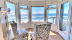 Une chambre d’angle avec vue sur l’océan, deux fauteuils à motifs et un lustre.