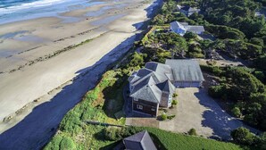 Une propriété située sur la côte, avec vue sur la plage, une maison dotée d’un toit en pente et un jardin bien entretenu.