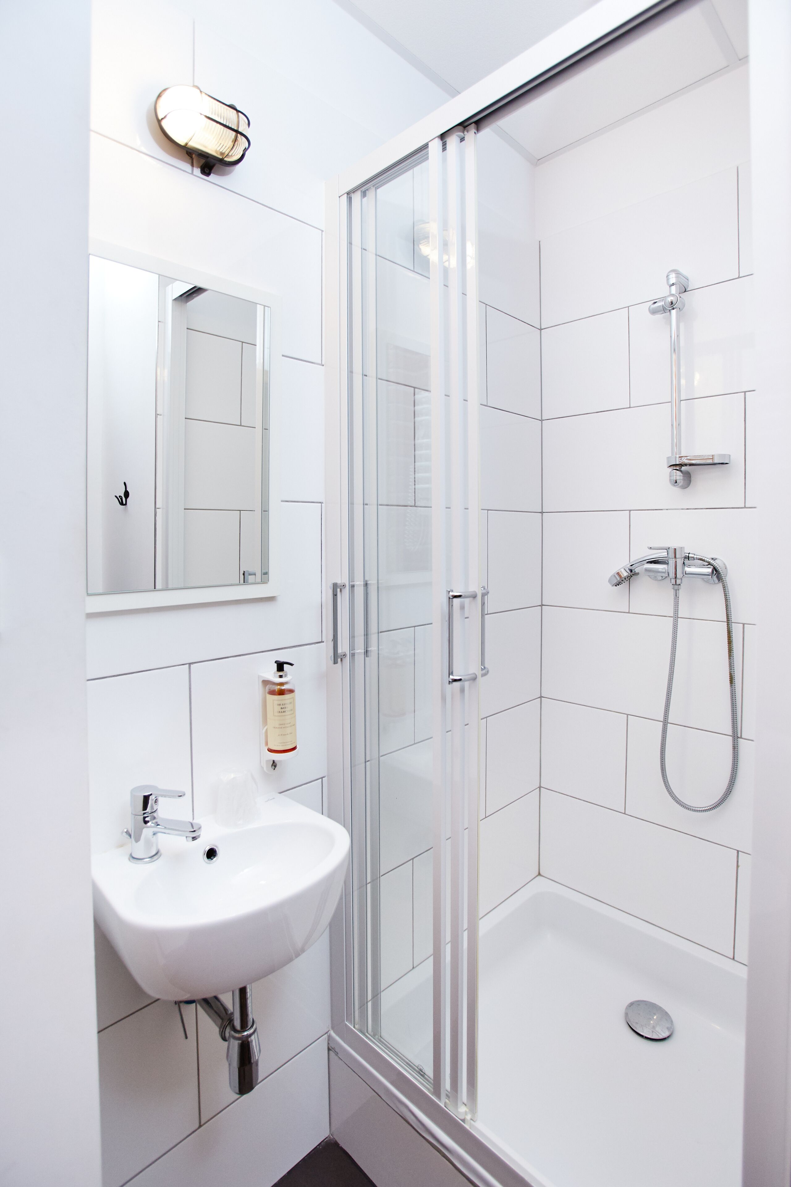 Un baño moderno con cabina de ducha de vidrio, lavabo blanco y espejo.