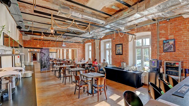A spacious restaurant with brick walls, exposed ceilings, and a variety of seating arrangements. - Koszary Arche Hotel (Gora Kalwaria)