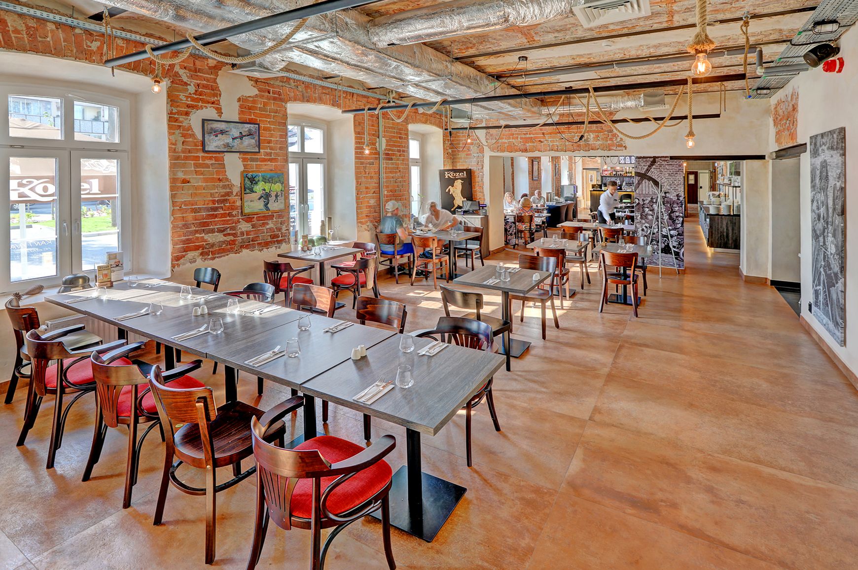 Un vaste espace dédié à la salle à manger, doté de hauts plafonds, de murs en briques apparentes et d’un mélange de meubles en bois et en métal.