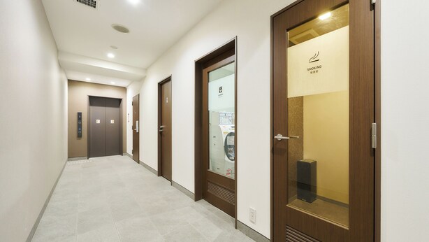 A hotel corridor with wooden doors, a reception area, and an elevator. - Rakuten STAY URBAN Nijo-jo (Kyoto)
