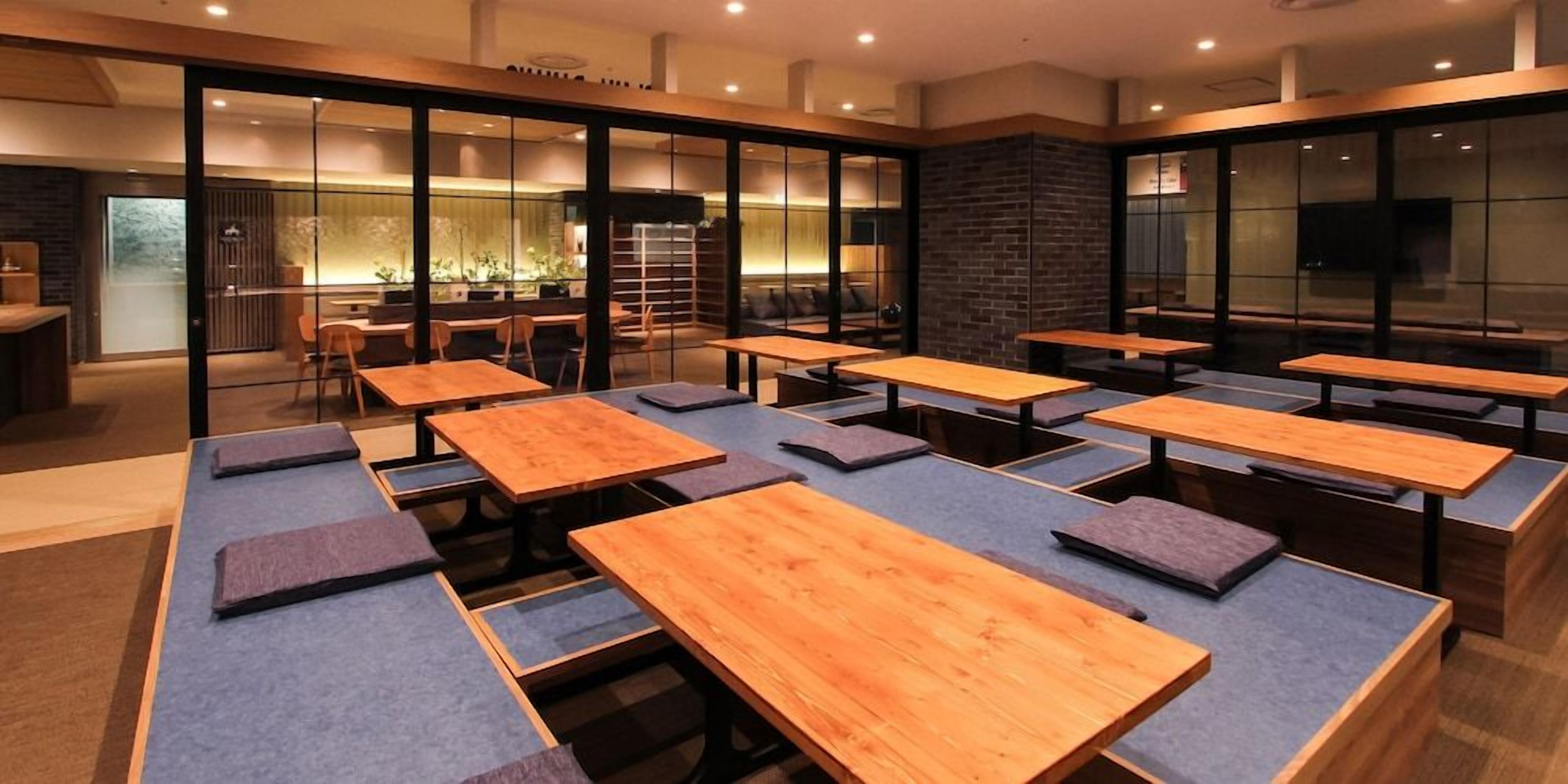 A modern dining area with multiple wooden tables and blue cushioned seating.