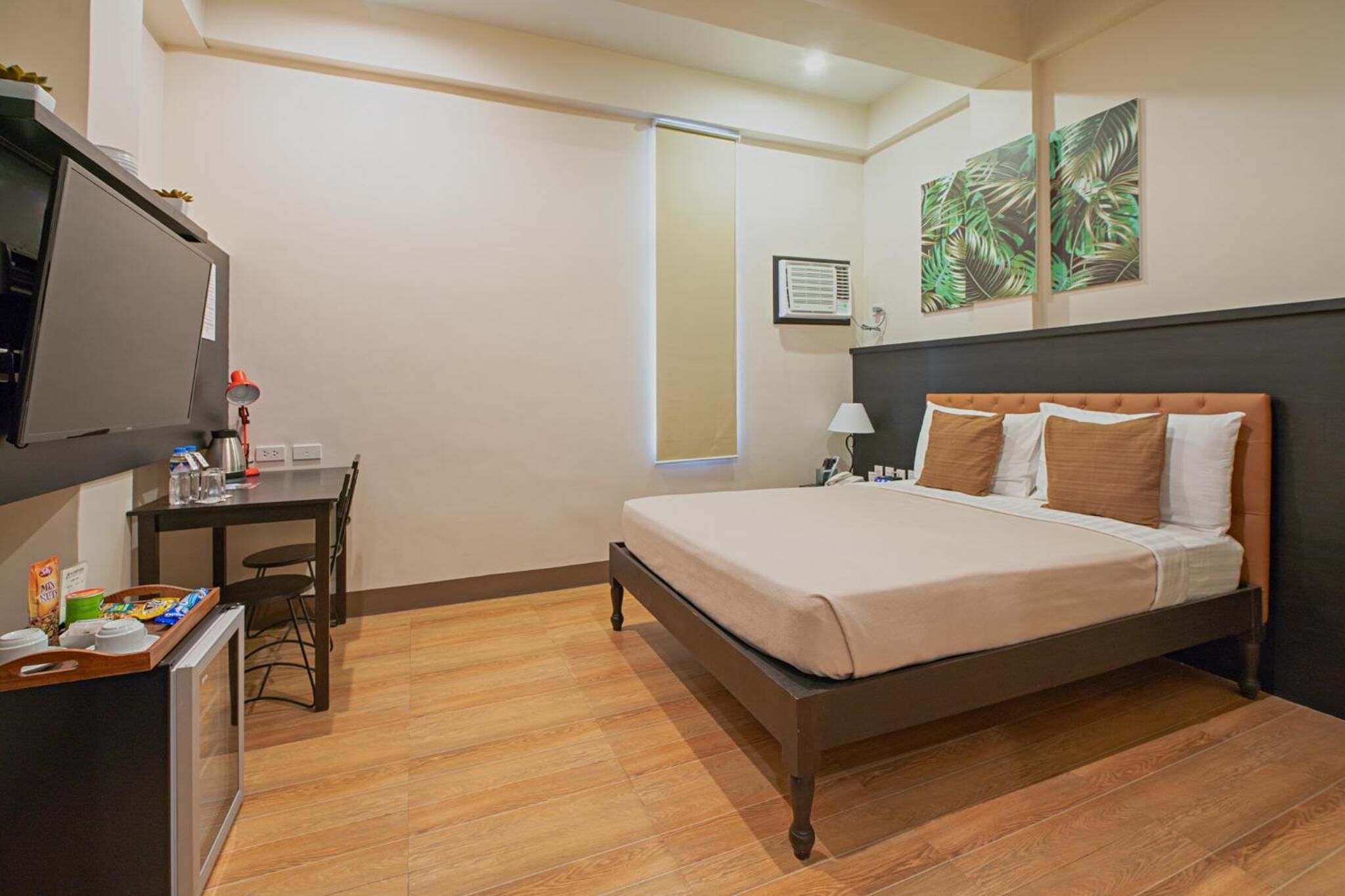 A hotel room with a bed, a desk, a television, and a window.