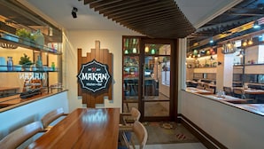 A restaurant interior with a wooden table and chairs, a sign reading "Maran Kitchen + Bar", and shelves with various items.