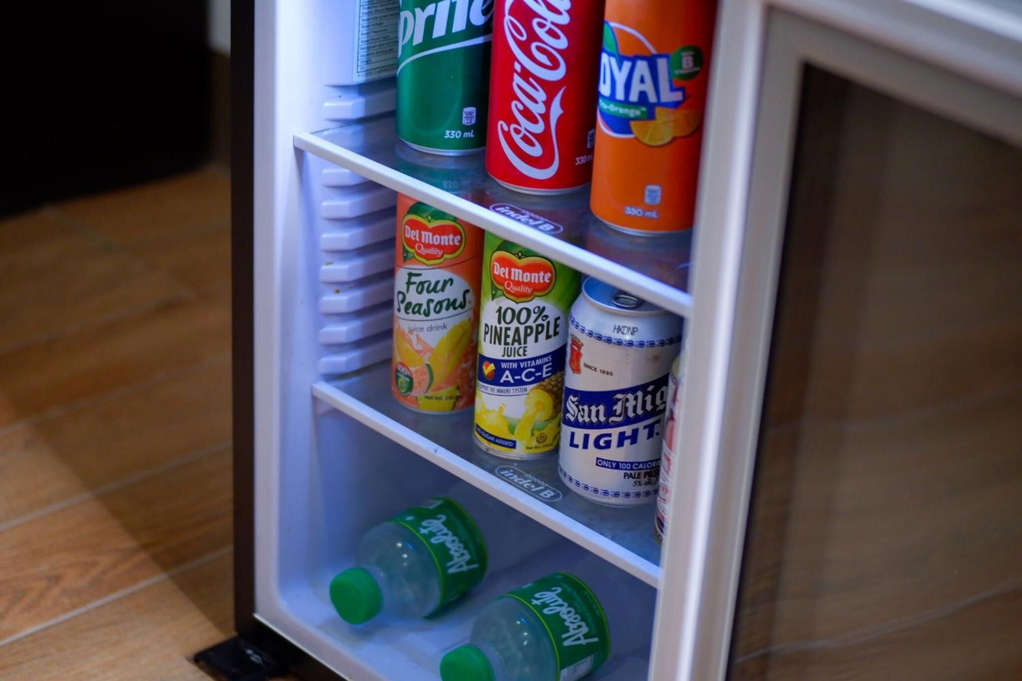 Ein Kühlschrank, gefüllt mit verschiedenen Getränken, darunter Coca-Cola, Del Monte Säfte und San Miguel Bier.