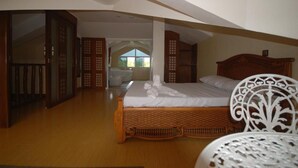 Une chambre avec un lit en bois, une chaise blanche et une vue sur la salle de bain.