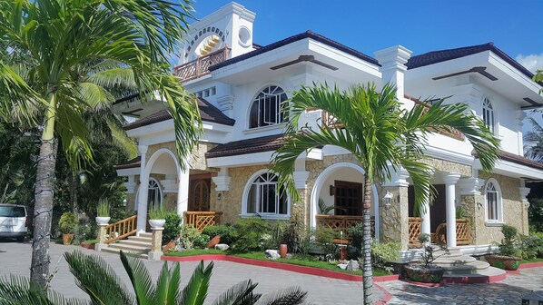 A large, two-story house with a stone facade, multiple windows, and a balcony. - La Parola Orchids Beach Resort (Patnongon)