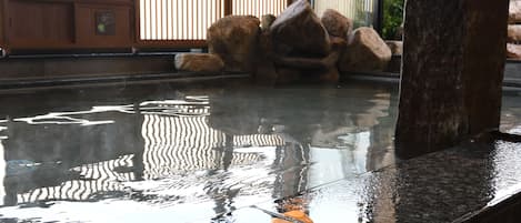 A stone water feature with rocks and a wooden fence in the background.