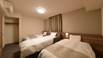 A hotel room with two single beds, a wooden headboard, a built-in wardrobe, and a ceiling light.
