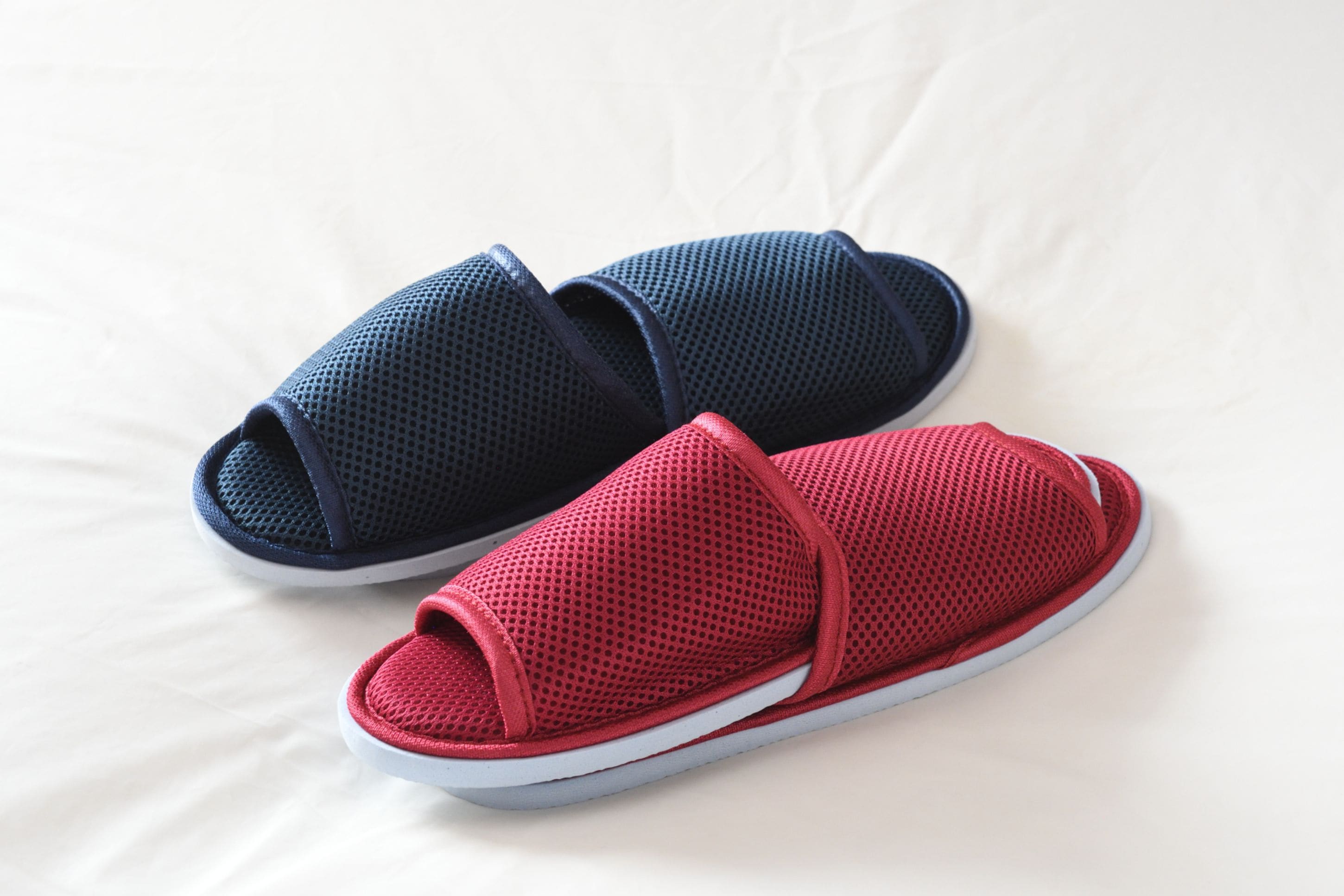 A pair of red and blue mesh slippers on a white surface.