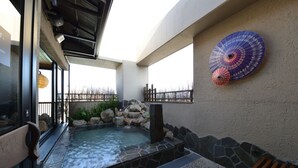 A hot tub area with a stone wall, a wooden bench, and a decorative umbrella on the wall.
