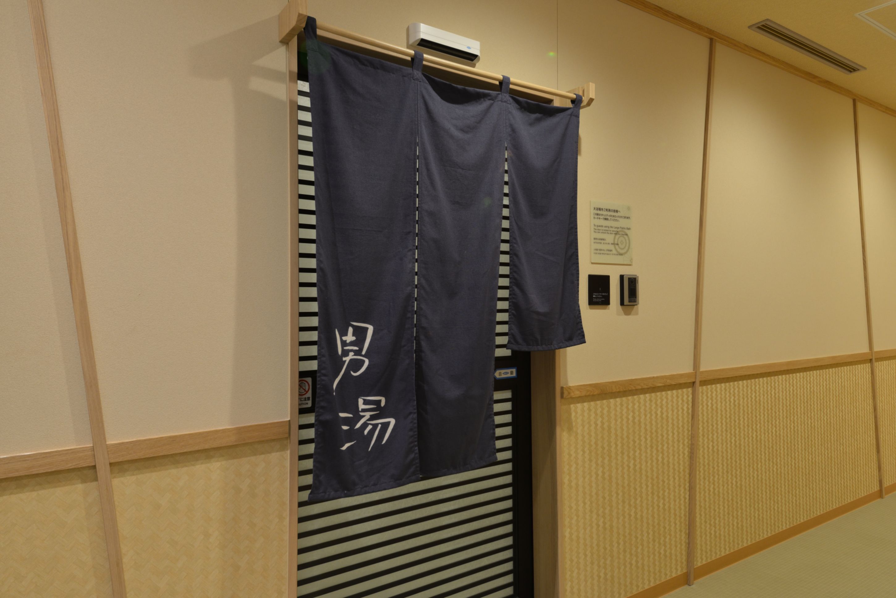 A room with a sliding door, a wall-mounted air conditioning unit, and a sign with Japanese characters.