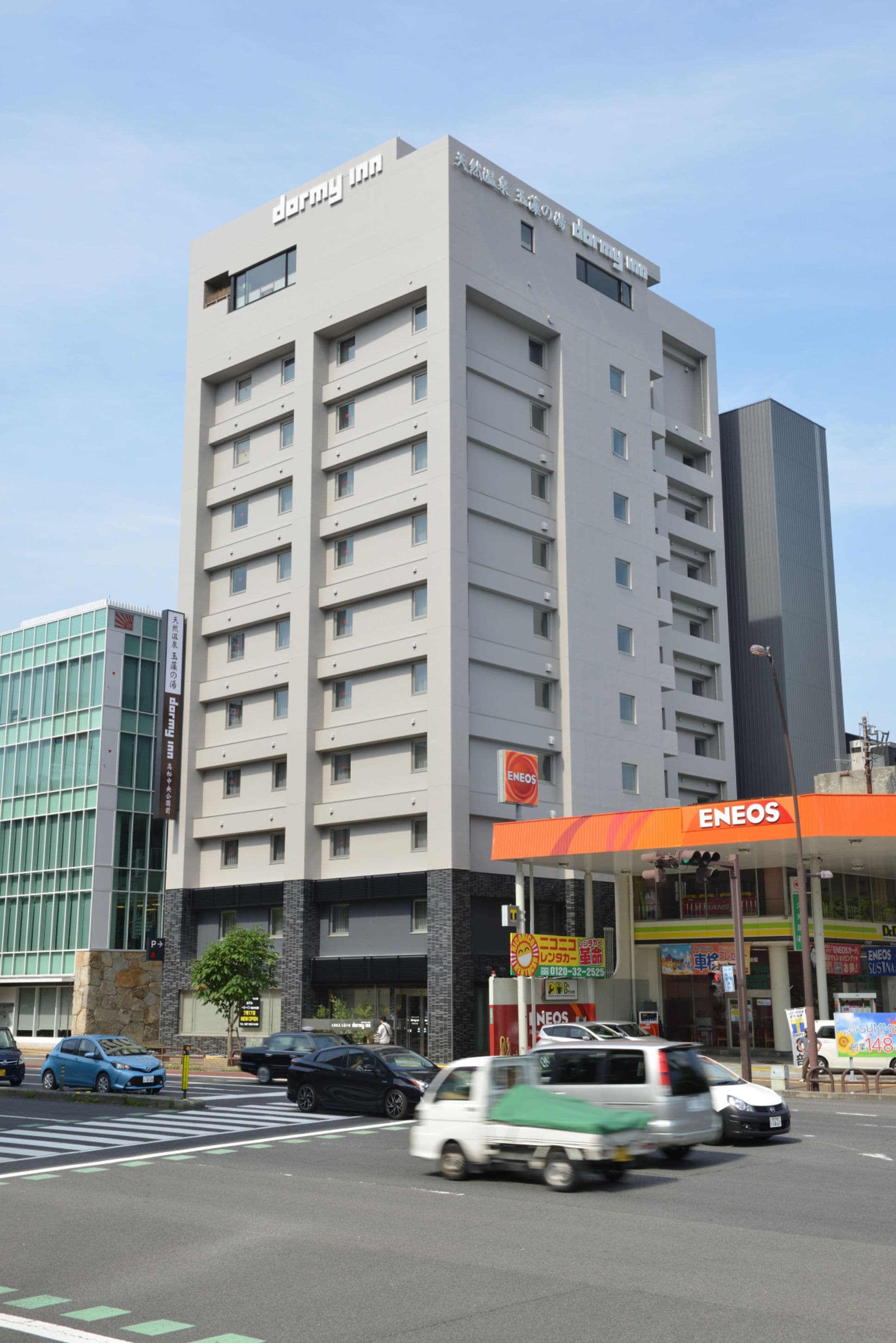Un edificio de varios pisos con un letrero que indica 'Darmy Inn' y 'ENEOS' en la planta baja.