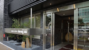 A modern building entrance with a sign for 'dormy inn'.