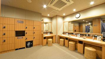 A hotel bathroom with wooden lockers, a sink, a mirror, and a clock.