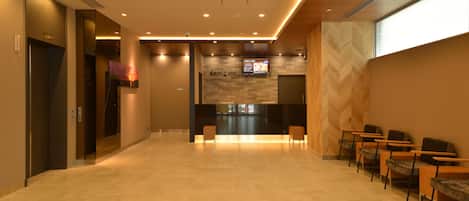 A spacious lobby with a reception desk, seating area, and a herringbone-patterned wall.
