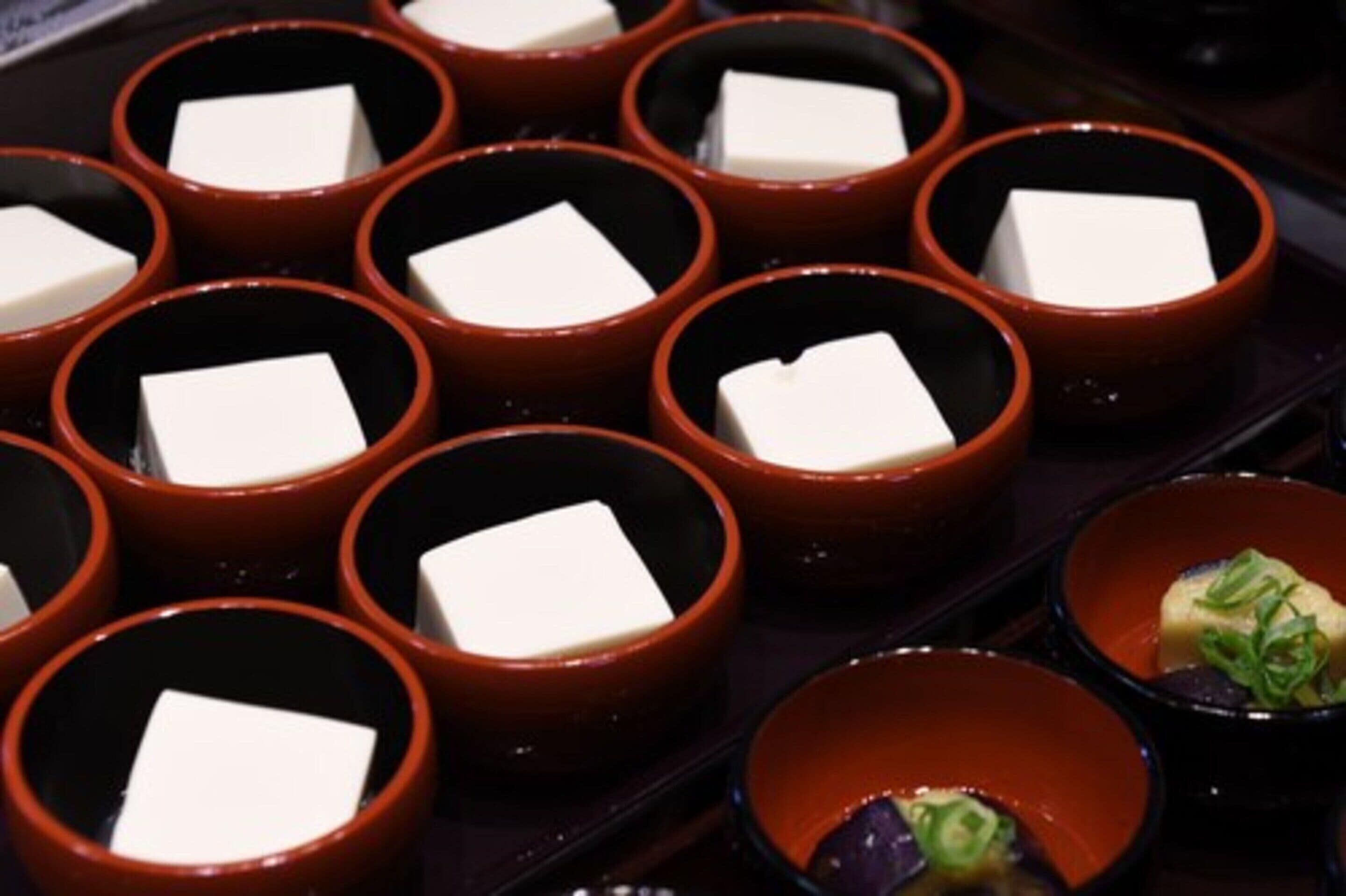 A tray of small bowls with tofu cubes and a bowl with sliced green onions.