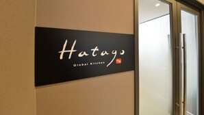A sign for "Hatago Global Kitchen" on a wall.