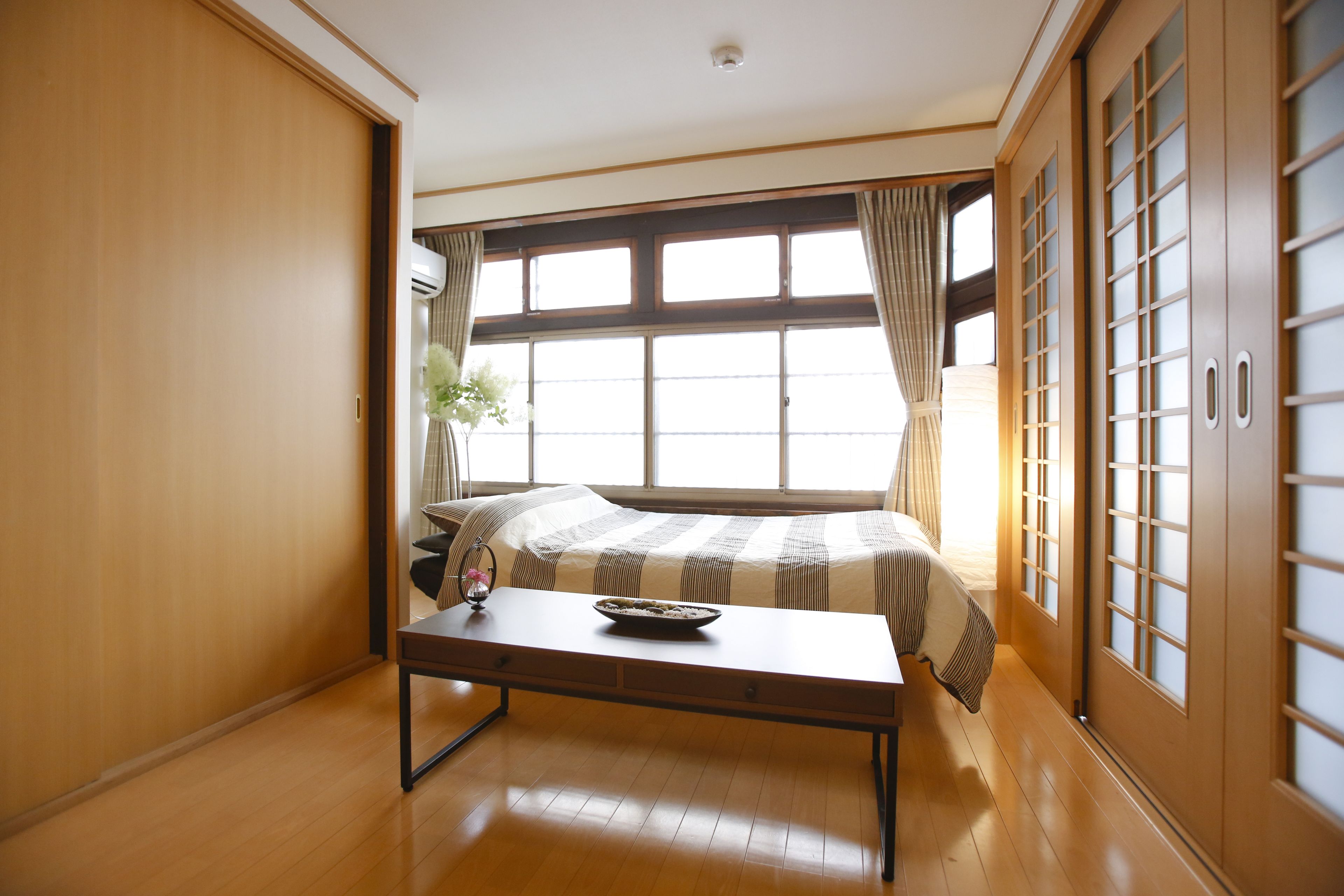 A room with a bed, a wooden table, and sliding doors.