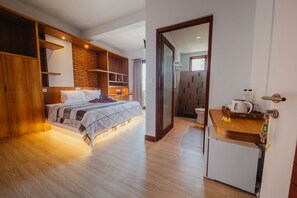 Une chambre moderne avec un grand lit, des étagères en bois et une petite kitchenette.