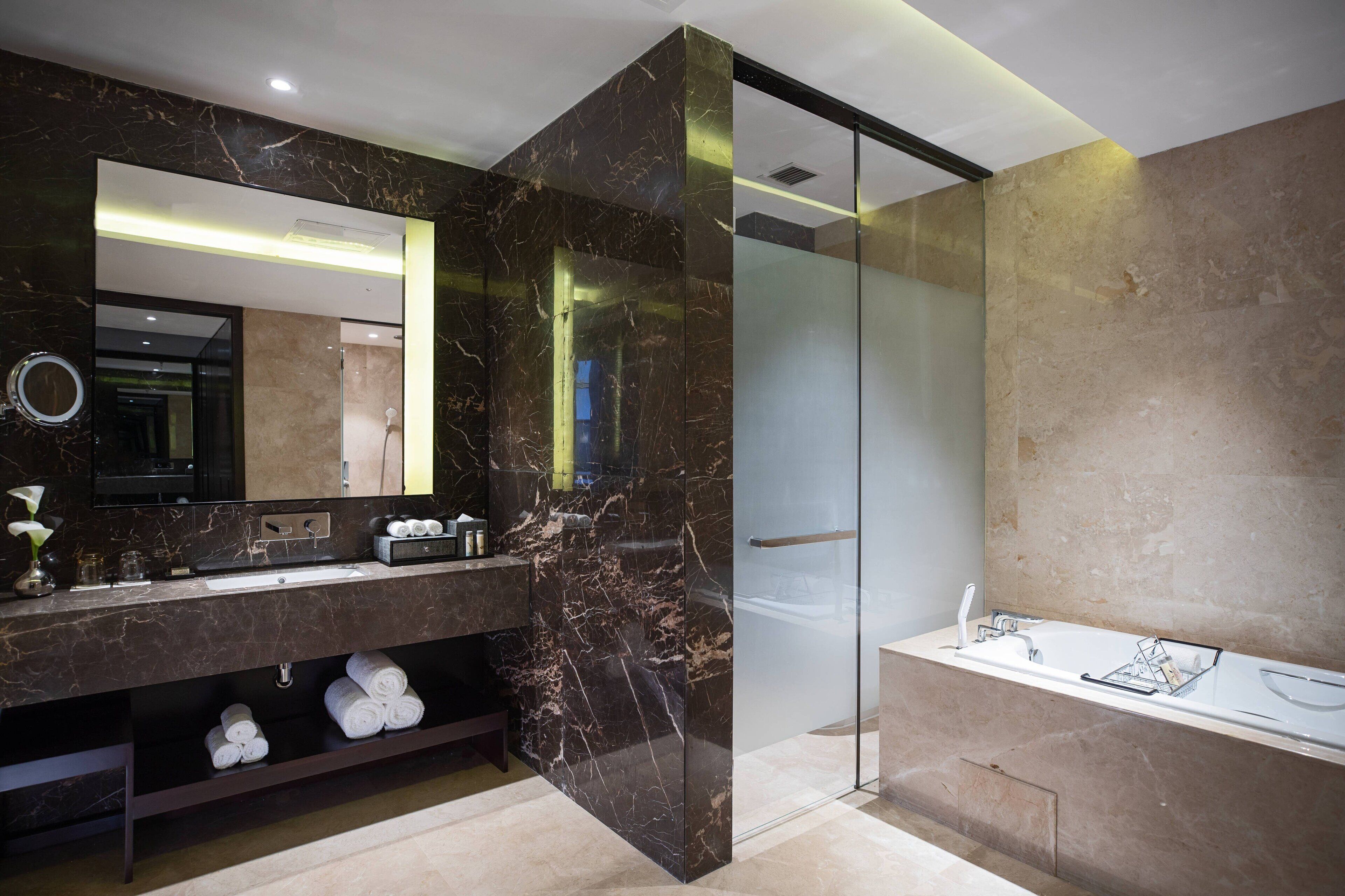 Une salle de bain moderne avec un meuble-lavabo en marbre, un grand miroir et une cabine de douche en verre.