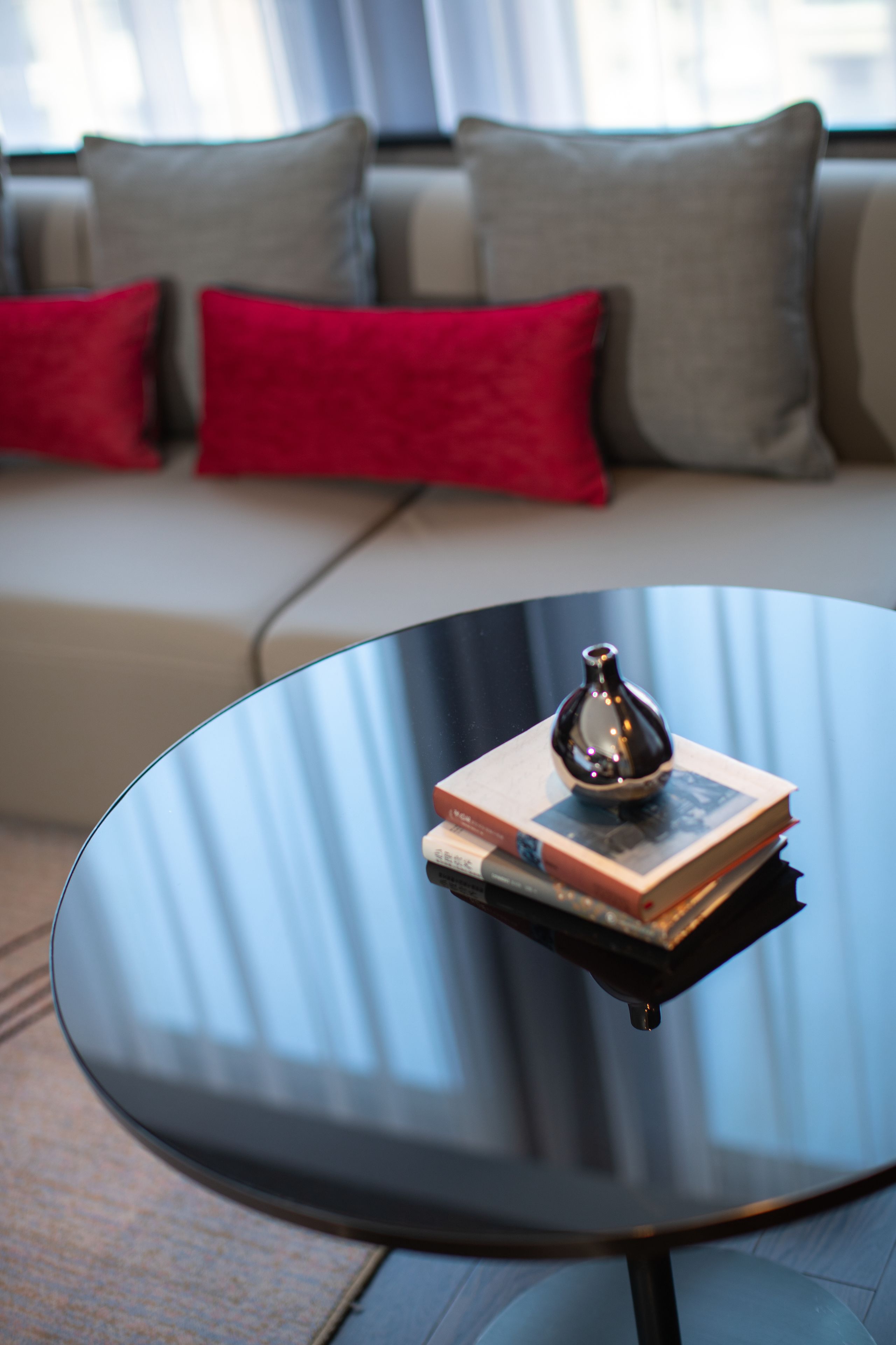 A modern living room with a glass coffee table, a book, and a decorative vase.