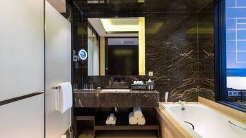 Un baño moderno con tocador de mármol, un espejo grande, una bañera y vistas al exterior.