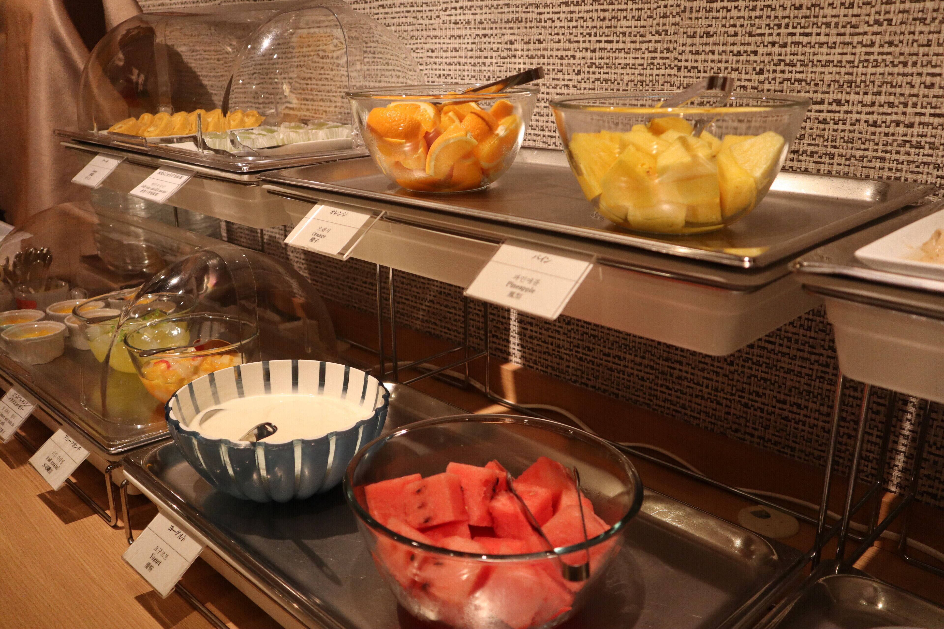 Un buffet proposant une variété de fruits et un bol bleu avec une cuillère.