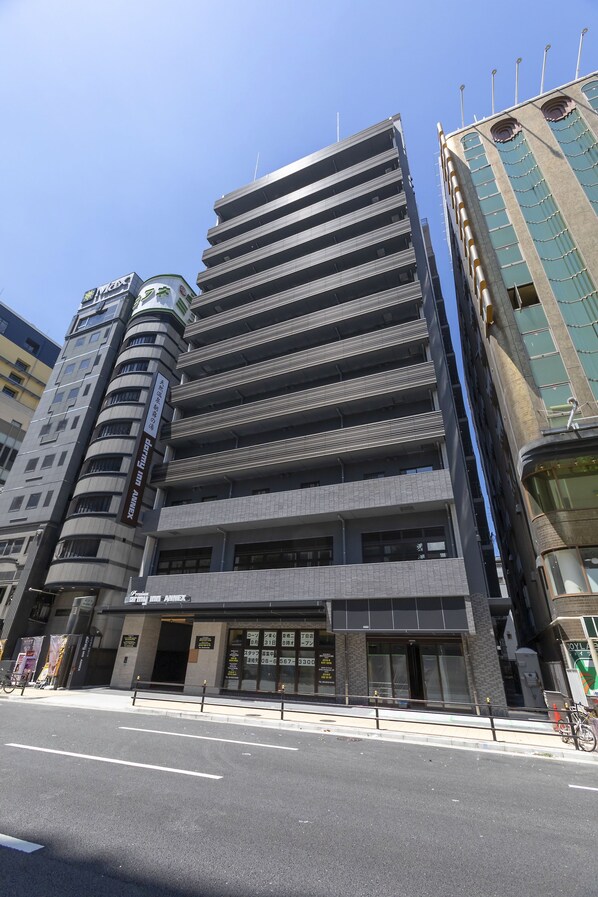 A multi-story building with a modern architectural design, featuring a prominent entrance with glass doors and a signboard.