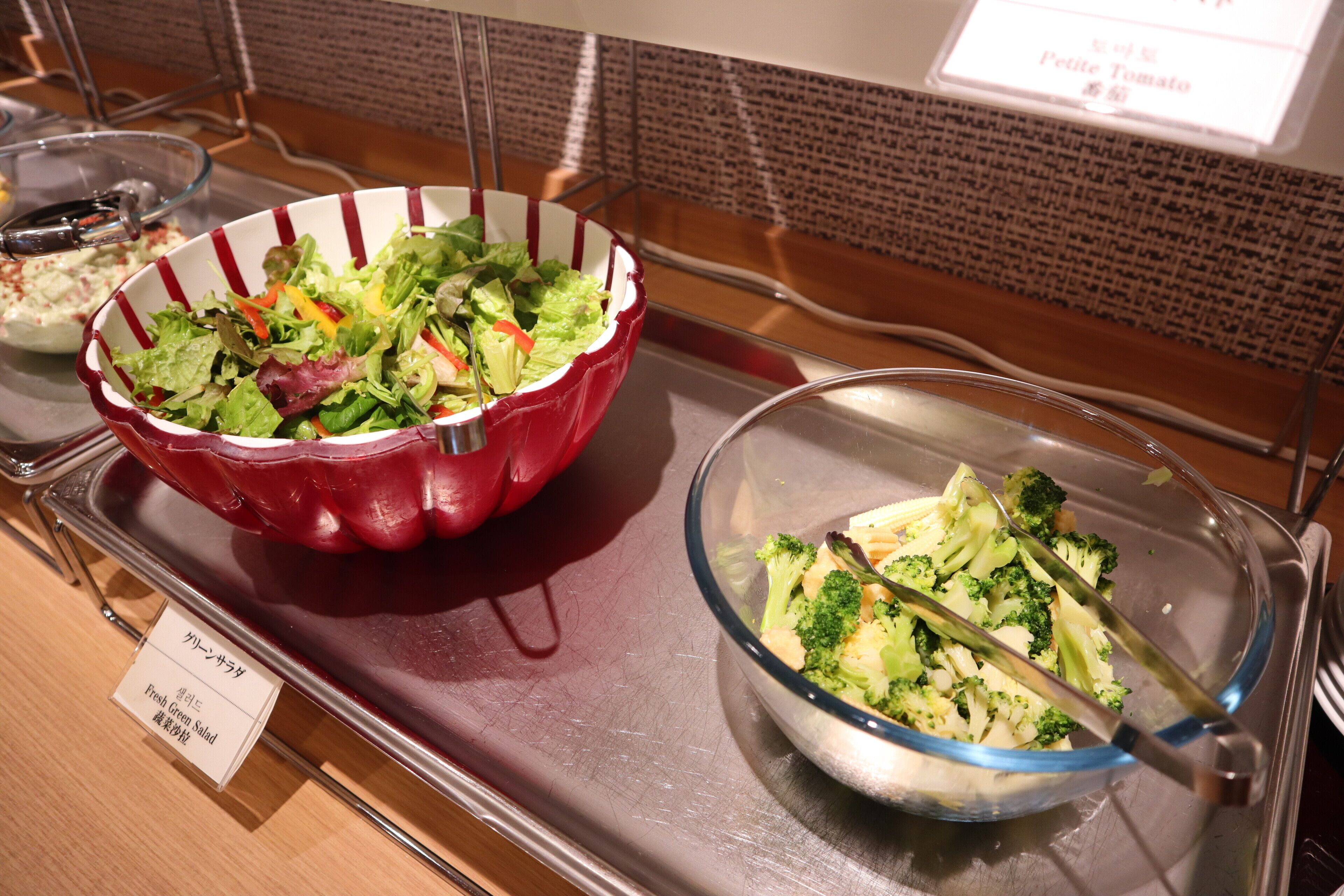 A buffet with a variety of salads, including a red bowl salad and a broccoli salad.