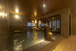 A hot spring bath with a stone centerpiece, wooden ceiling, and tiled walls. - Dormy Inn Premium Namba ANNEX Natural Hot Spring (Osaka)
