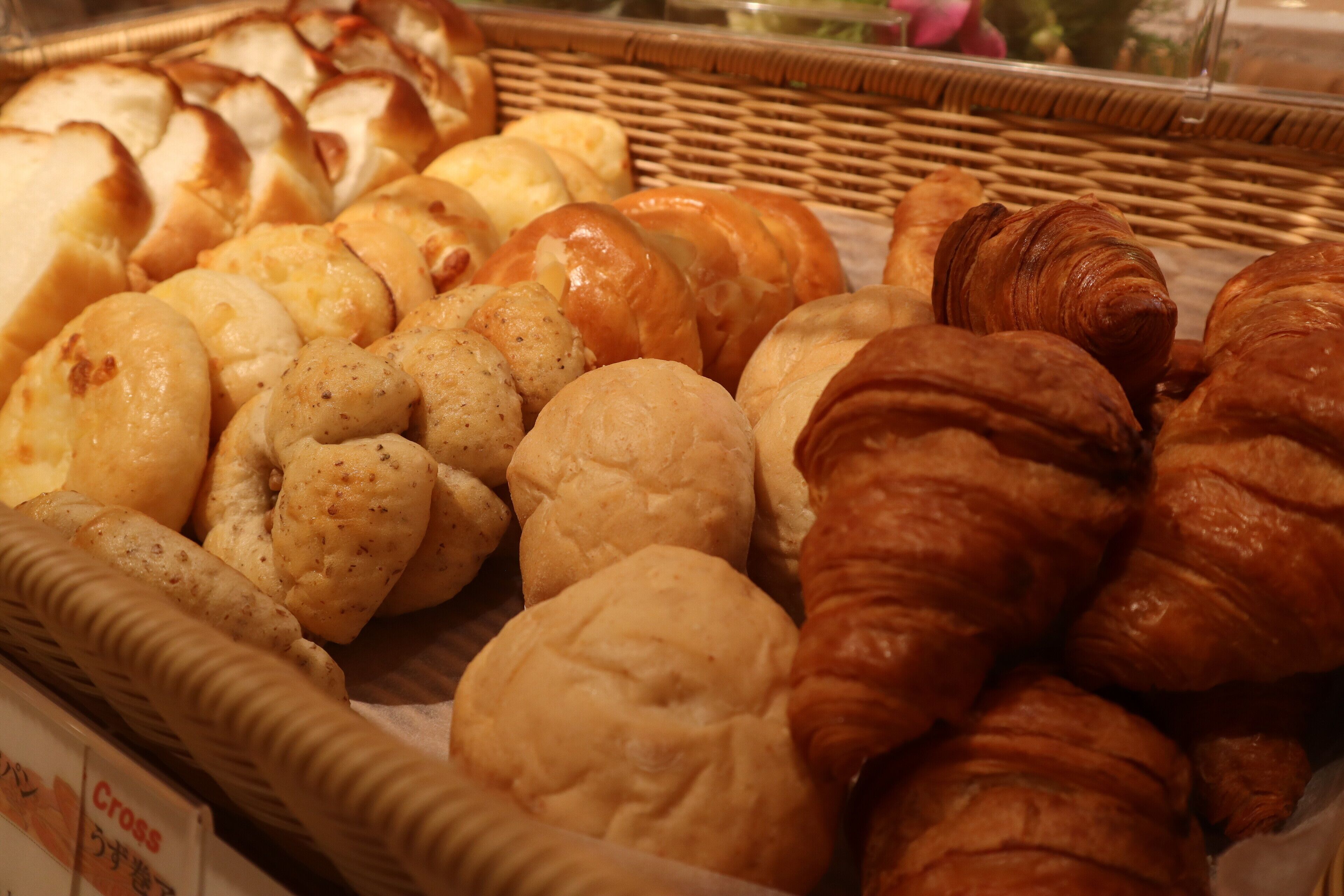 A variety of baked goods including croissants and bread, displayed in a wicker basket.