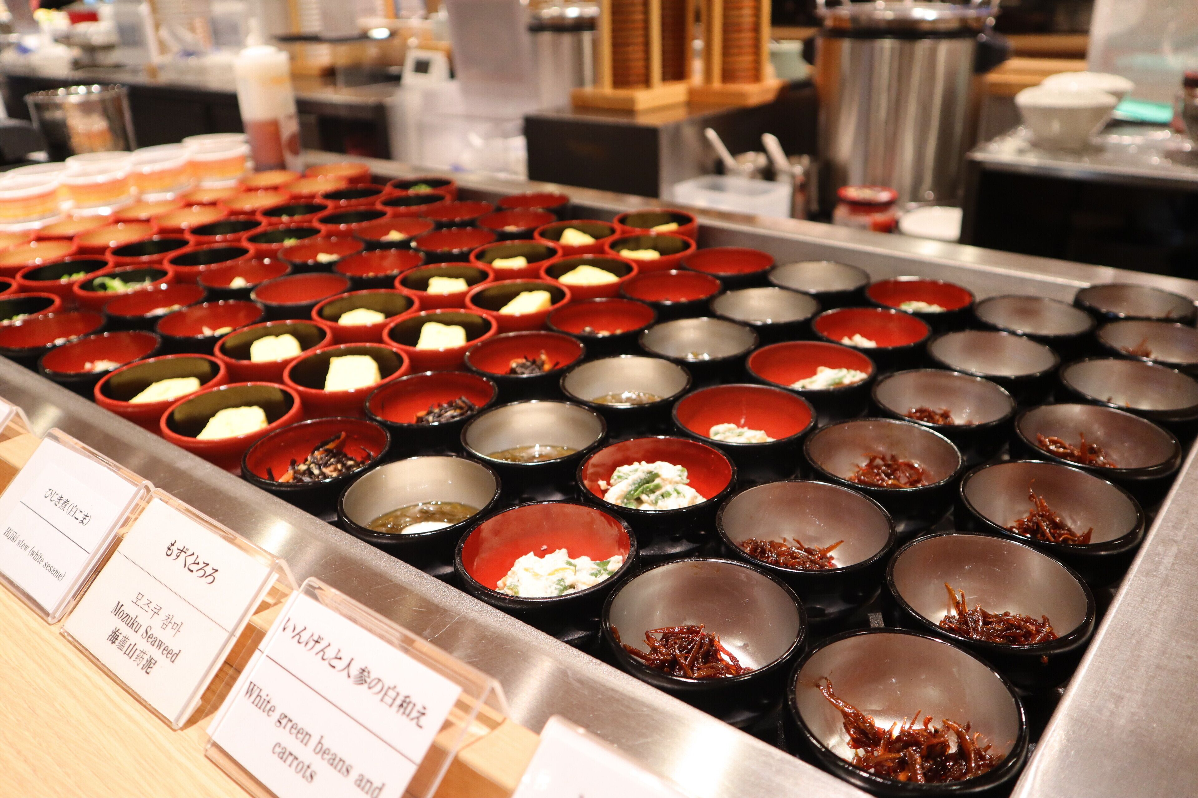 A buffet with various dishes in small bowls, each labeled with a name.