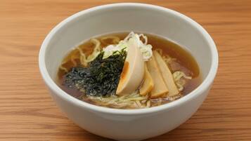 Een kom ramen met zeewier en tofu op een houten tafel.