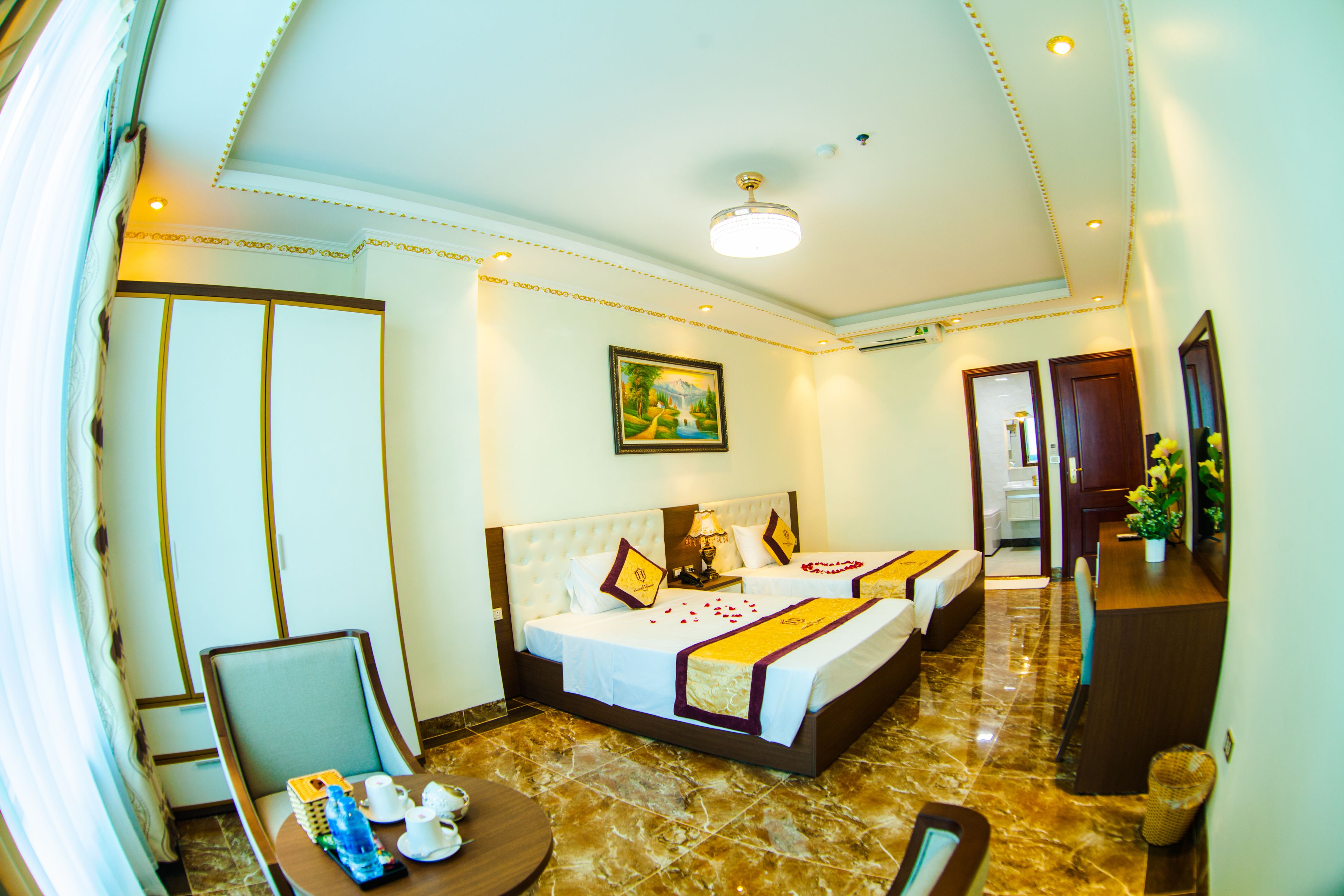 A hotel room with a large bed, a desk, a chair, and a bathroom visible through an open door.