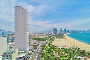 A tall hotel with a modern design, located near a beach and a busy road. - Imperial Nha Trang Hotel (Nha Trang)