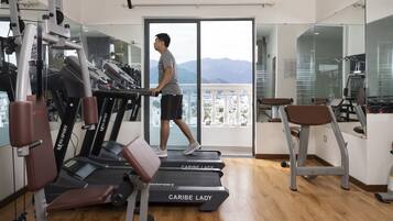 Un gimnasio con cintas de correr, máquinas de pesas y un espejo grande.