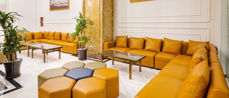 A modern lobby with a large sectional sofa, a coffee table, and potted plants.