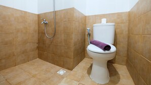 A bathroom with a shower, toilet, and a towel rack. - Studio at Green Pramuka City Serene Apartment Living By Travelio (Jakarta)