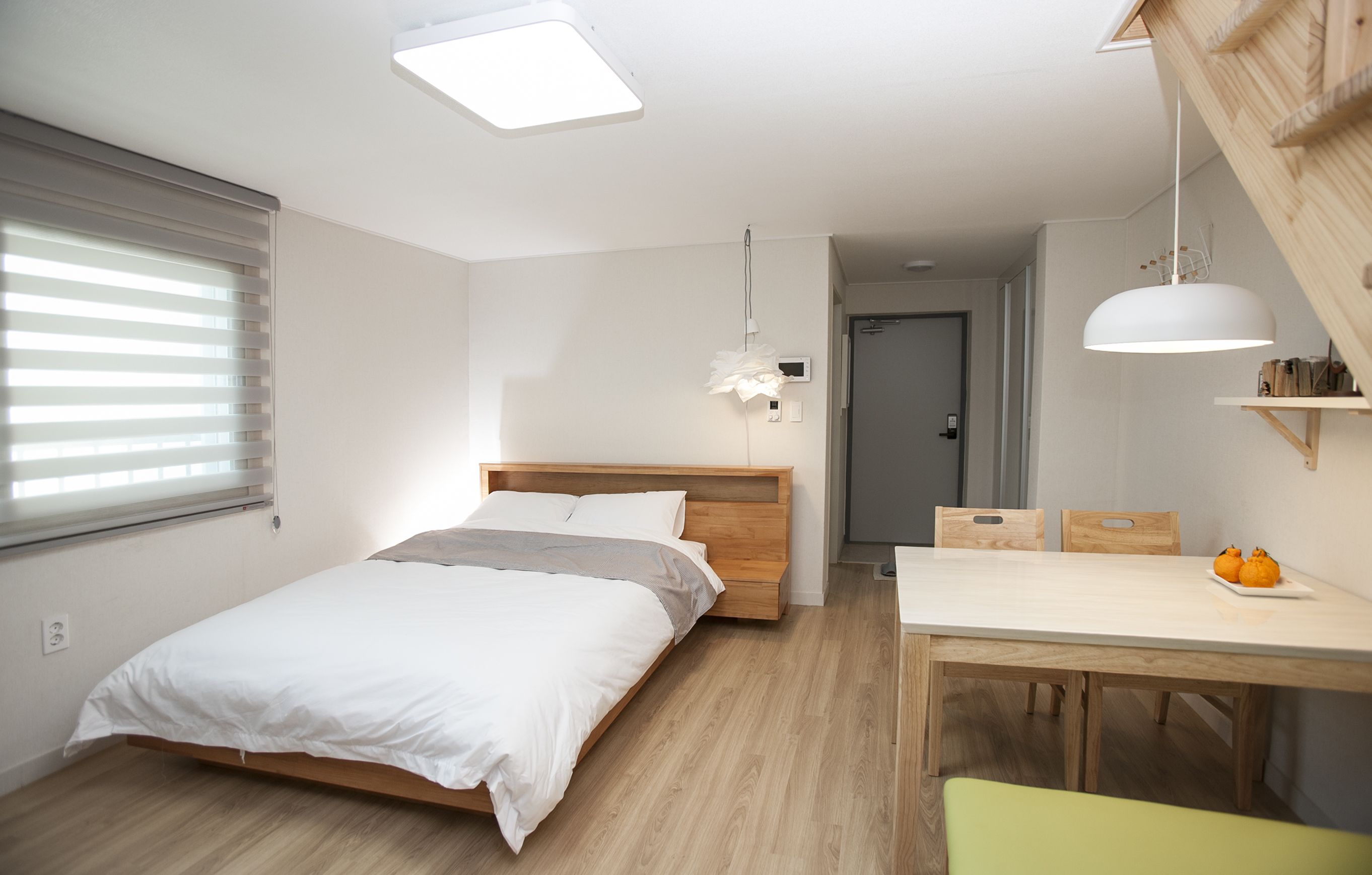 A bedroom with a bed, bedside table, and a dining area with a table and chairs.
