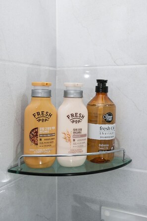 Kolme pulloa Fresh Pop -tuotteita lasihyllyllä kylpyhuoneessa.